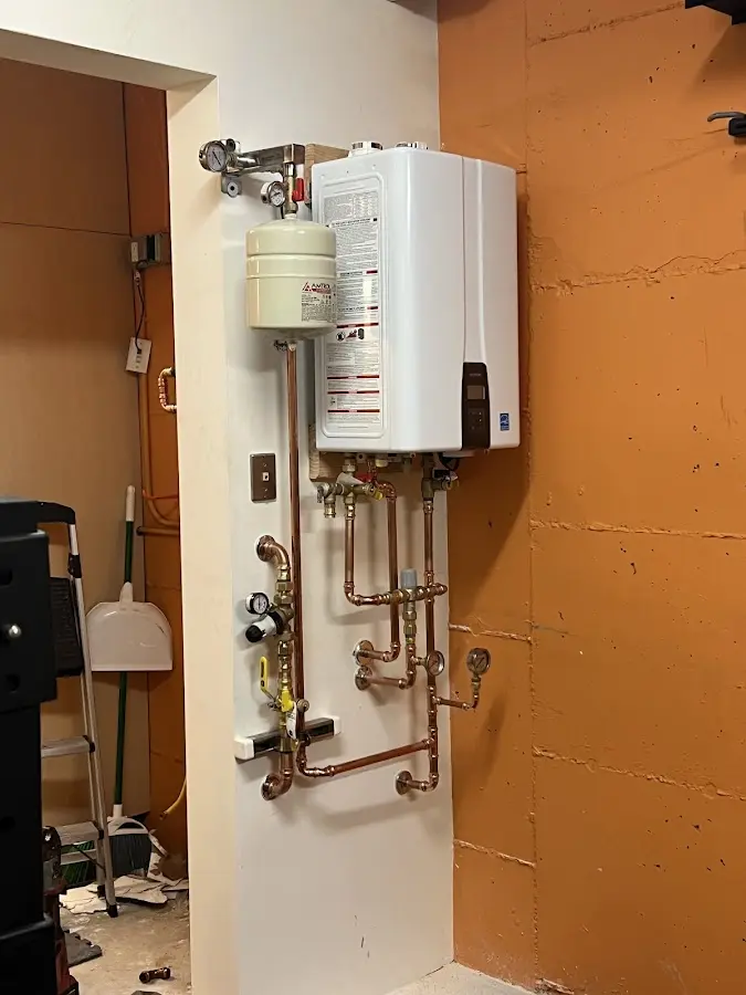 Plumbing technician inspecting water heater connections in La Follette